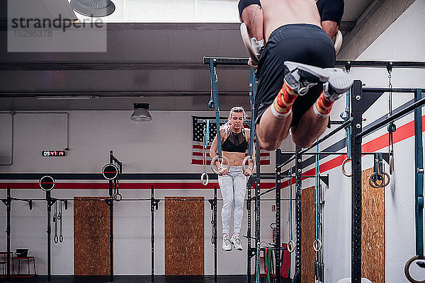 Junges Paar balanciert auf Gymnastikringen in der Turnhalle