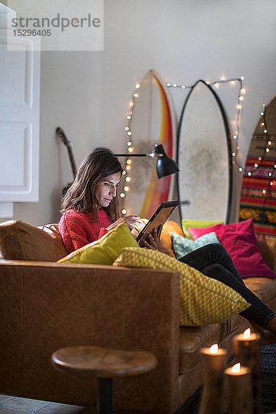 Junge Frau auf Wohnzimmer-Sofa mit digitalem Tablet-Touchscreen