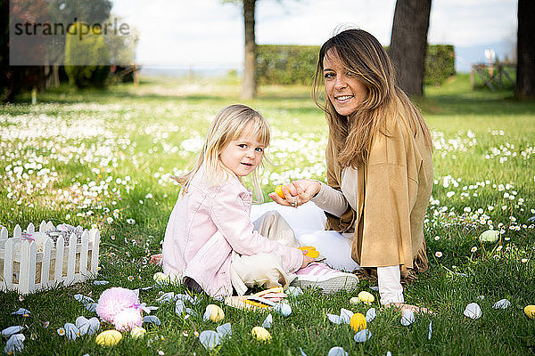 Mutter und Tochter entspannen sich im Wildblumenfeld nach der Ostereiersuche  Porträt  Arezzo  Toskana  Italien