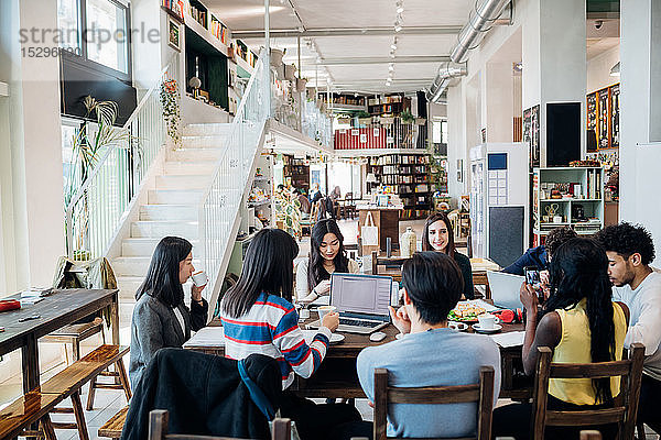 Männliche und weibliche Geschäftsteambesprechung beim Arbeitsessen am Cafétisch