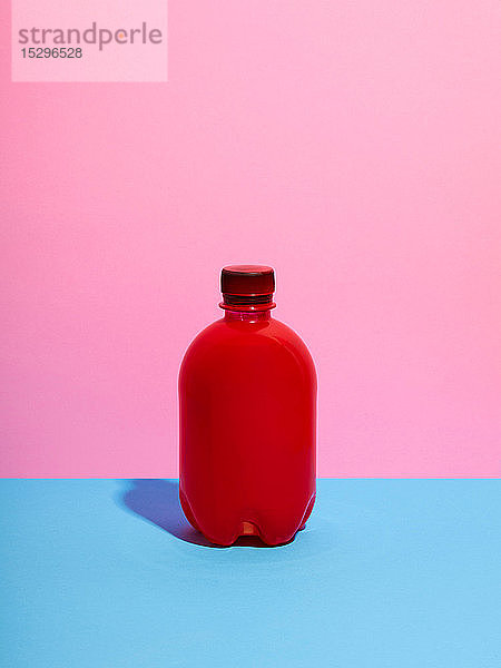Stilleben mit roter Plastikflasche und rosa Hintergrund