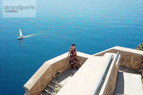 Junge Frau genießt den sonnigen Tag auf See  Segelboot im Hintergrund  Alghero  Sardinien  Italien