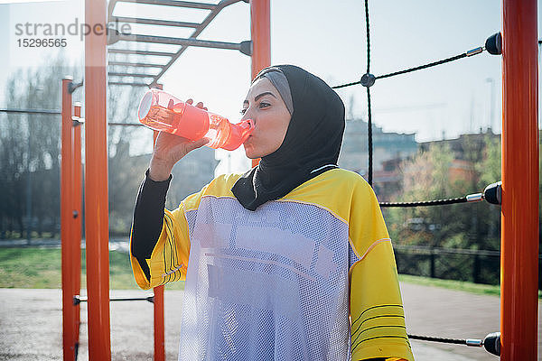 Calisthenics-Kurs im Fitnessstudio im Freien  junge Frau trinkt aus der Wasserflasche