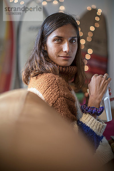 Junge Frau im Strickpulli  die sich auf dem Wohnzimmersofa entspannt und über die Schulter schaut  Porträt