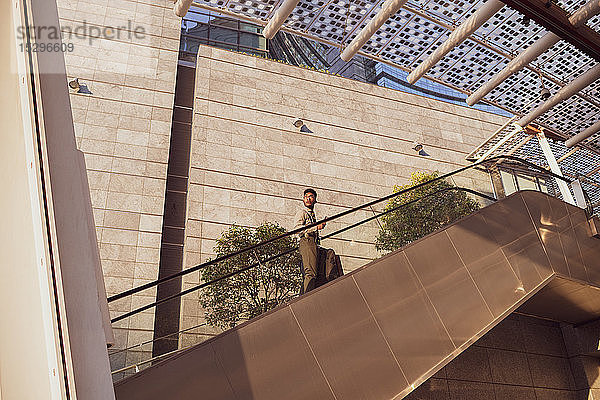 Geschäftsmann besteigt Rolltreppe eines Bürogebäudes  Mailand  Lombardei  Italien