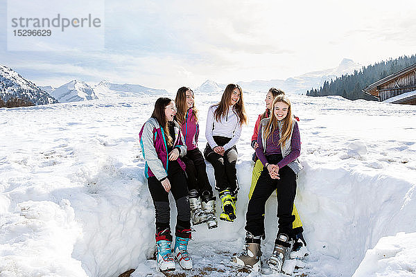 Fünf jugendliche Skifahrerinnen sitzen lachend in verschneiter Landschaft  Tirol  Steiermark  Österreich