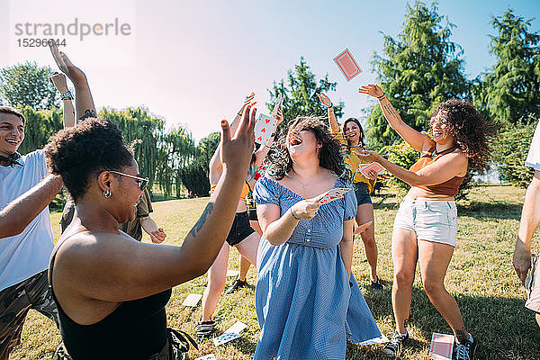 Gruppe von Freunden tanzt  wirft im Park Spielkarten in die Luft
