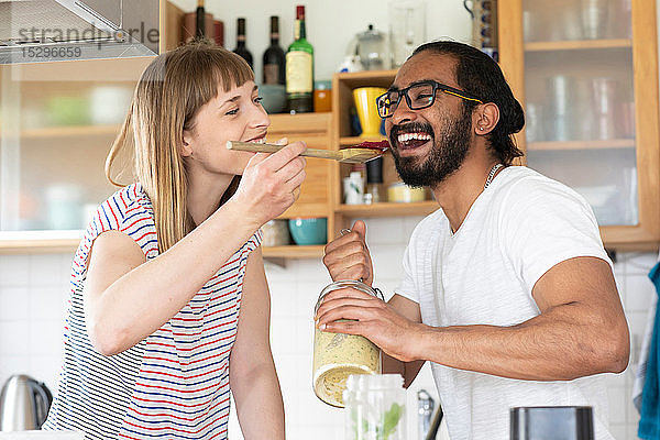 Frau füttert Mann mit Holzlöffel in Küche