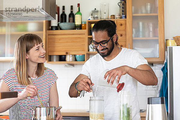 Multi-ethnisches Paar redet und kocht in der Küche