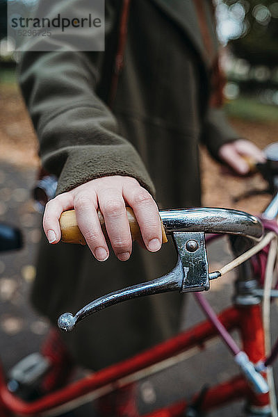 Junge Frau schiebt Fahrrad im Herbstpark  Nahaufnahme der Hand am Lenker