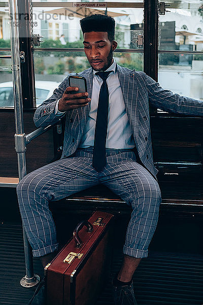 Geschäftsmann benutzt Smartphone in der Straßenbahn in der Stadt