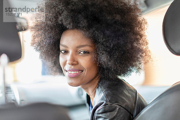 Glückliche junge Frau mit Afro-Haaren auf dem Beifahrersitz eines Autos  Porträt