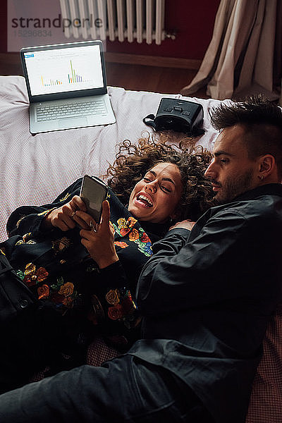 Ehepaar benutzt Smartphone am Bett
