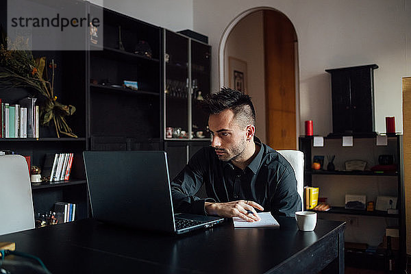 Mann benutzt Laptop im Heimbüro