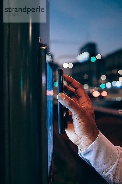 Geschäftsmann benutzt digitales Informationssystem an Bushaltestelle