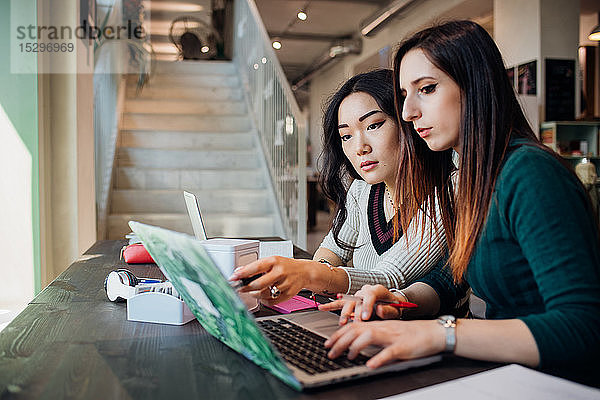 Junge Geschäftsfrauen mit Laptop am Café-Tisch