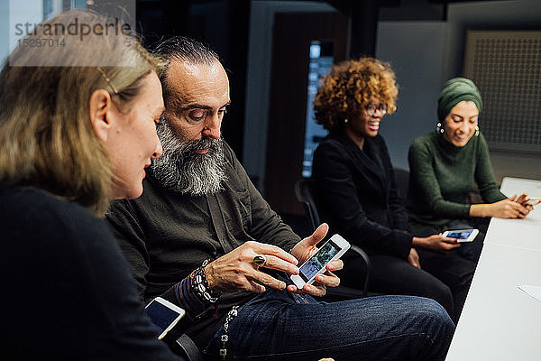 Geschäftspartner nutzen Smartphone bei Besprechung im Büro