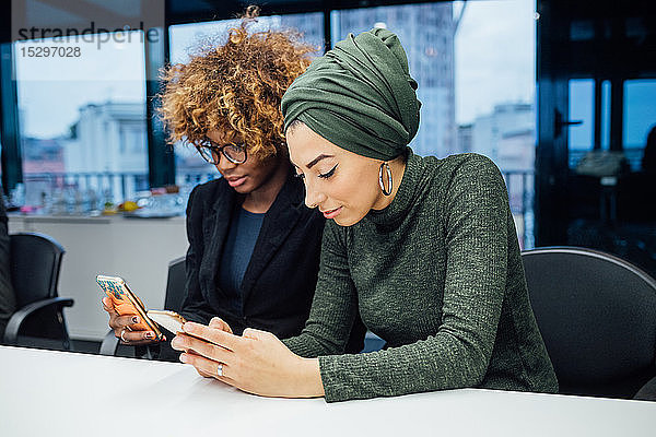 Geschäftspartner nutzen Smartphone bei Besprechung im Büro