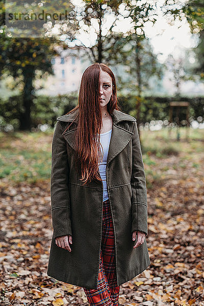 Junge Frau mit langen roten Haaren im Herbstpark  Porträt