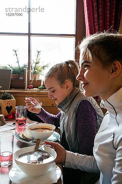 Zwei jugendliche Skifahrerinnen essen in Hütte