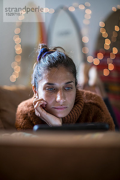 Junge Frau auf Wohnzimmersofa liegend und auf Laptop starrend  flacher Fokus