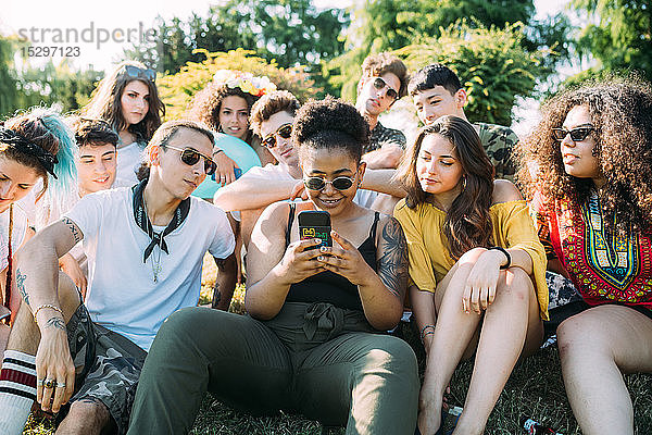 Gruppe von Freunden benutzt Smartphone im Park