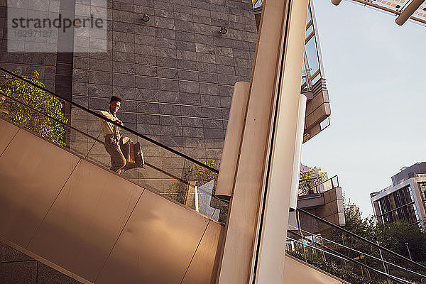 Geschäftsmann fährt die Rolltreppe eines Bürogebäudes herunter  Mailand  Lombardei  Italien