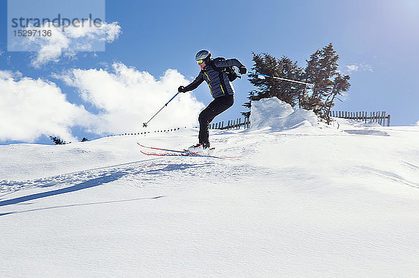 Erwachsener Mann fährt mit Skiern den schneebedeckten Berg hinunter  Steiermark  Tirol  Österreich