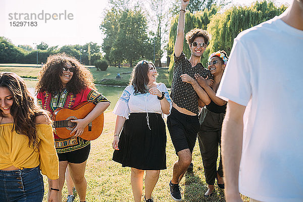 Gruppe von Freunden tanzt  spielt Gitarre im Park