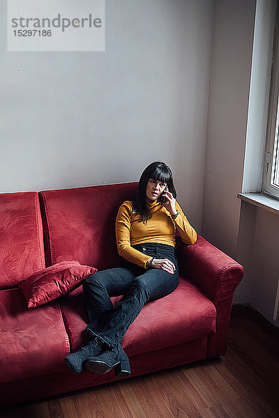 Frau spricht mit Smartphone auf dem Sofa