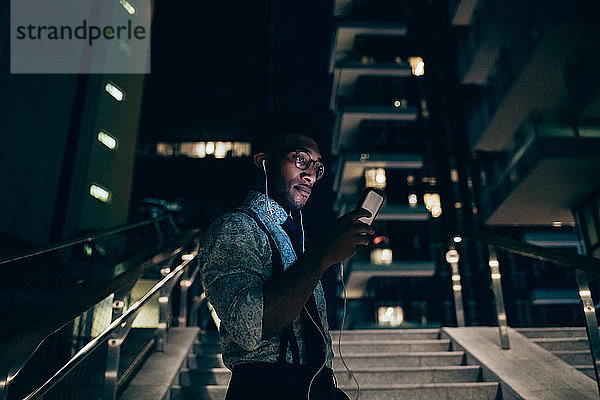 Geschäftsmann mit Smartphone auf der Treppe eines Bürogebäudes