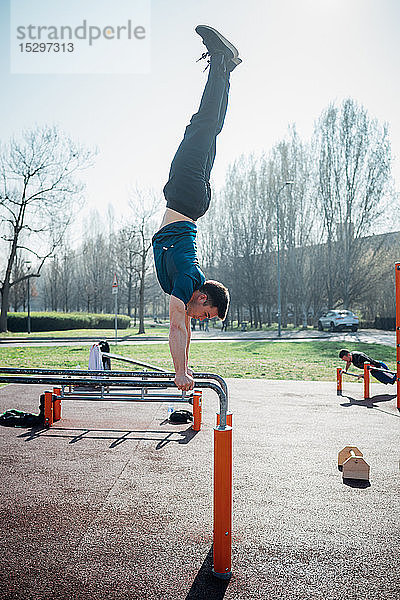 Gymnastik im Freien  junger Mann macht Handstand am Barren