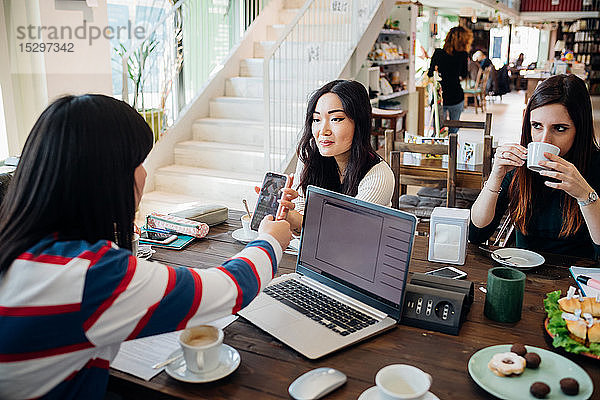 Treffen des weiblichen Geschäftsteams bei einem Arbeitsessen am Café-Tisch