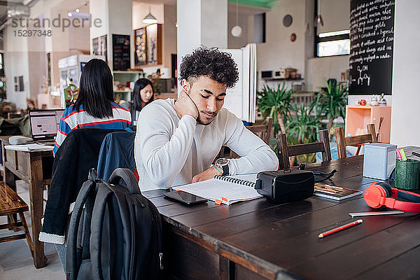 Junger Geschäftsmann arbeitet ferngesteuert am Laptop am Cafétisch