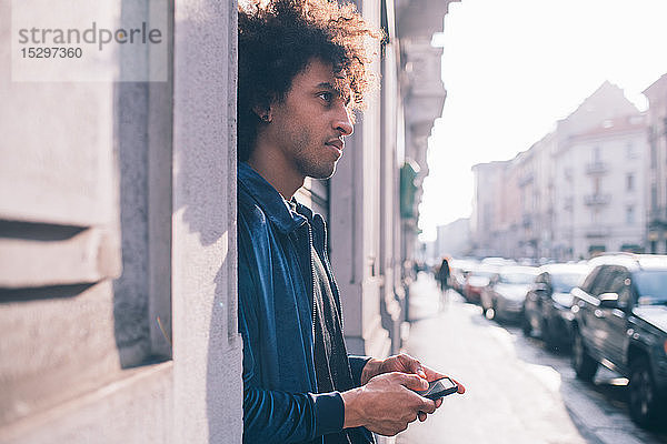 Junger Mann benutzt Smartphone auf Bürgersteig  Mailand  Lombardei  Italien
