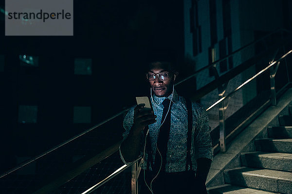 Geschäftsmann mit Smartphone auf der Treppe eines Bürogebäudes