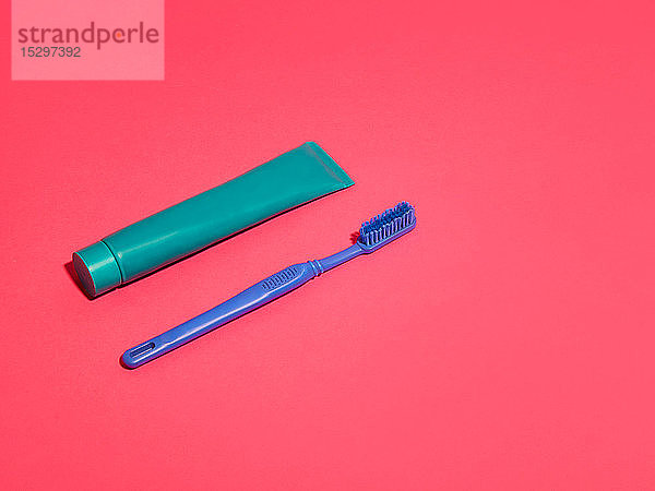 Zahnbürste und Zahnpasta auf rotem Hintergrund