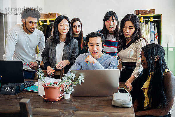 Gruppe junger Geschäftsleute betrachtet Laptop in Bürobesprechung