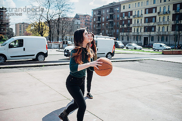 Junge Freundinnen spielen Basketball auf dem Stadtplatz