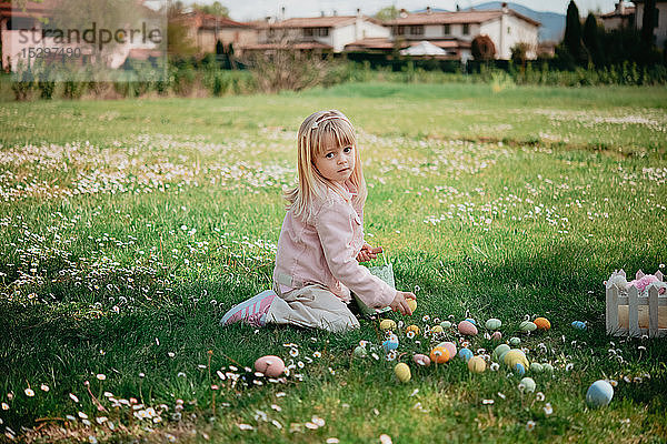 Hübsches Mädchen sitzt im Feld und sammelt Ostereier auf  Porträt  Arezzo  Toskana  Italien