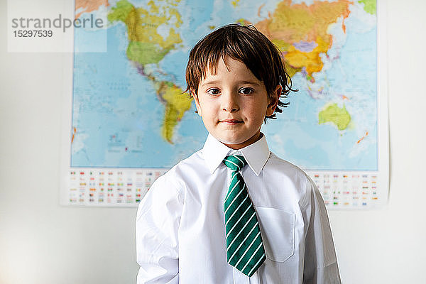 Porträt eines Jungen in Schuluniform  Weltkarte im Hintergrund