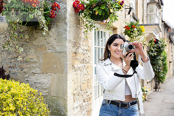 Junge Frau auf Dorfstraße fotografiert mit Digitalkamera  Cotswolds  England