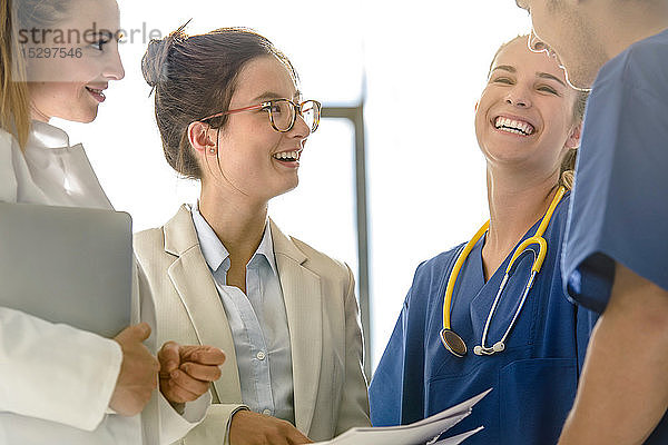 Junge weibliche und männliche Nachwuchsärzte plaudern und lachen im Krankenhaus
