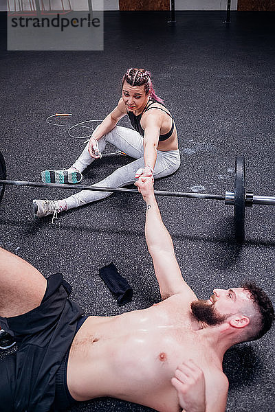 Junge Frau und Mann trainieren zusammen  stoßen sich im Fitnessstudio mit den Fäusten