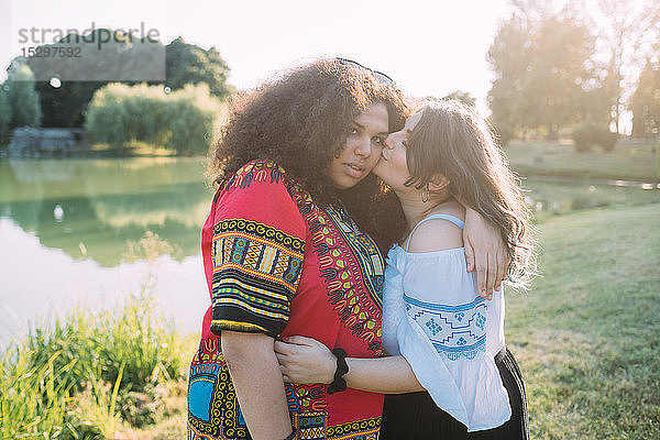 Freunde umarmen und küssen sich im Park auf die Wange