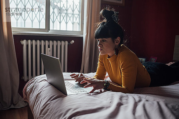 Frau benutzt Laptop im Bett