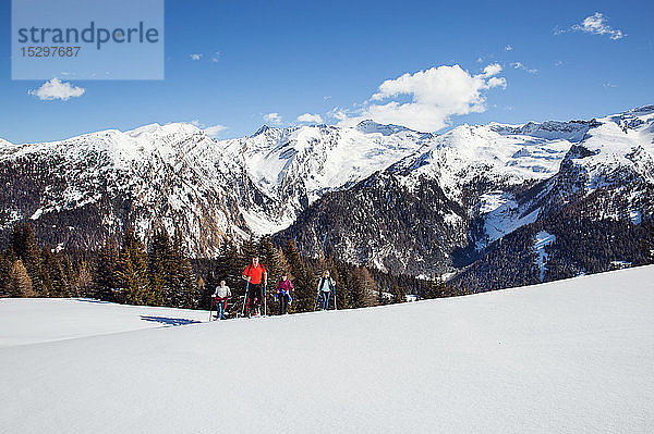 Reifes Paar und Töchter beim Schneeschuhwandern in schneebedeckter Berglandschaft  Steiermark  Tirol  Österreich