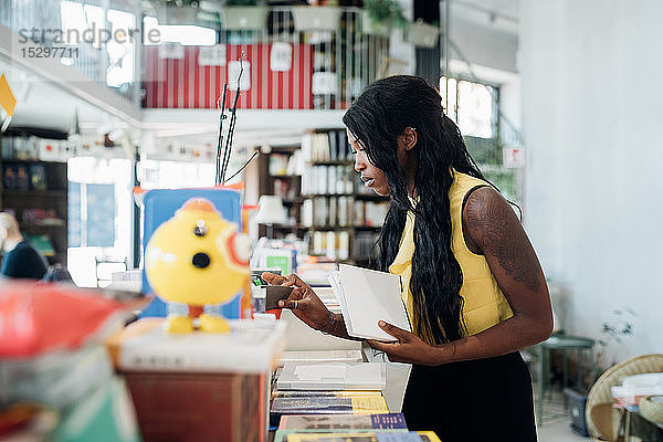 Junge Geschäftsfrau betrachtet Bücher im Buchladen