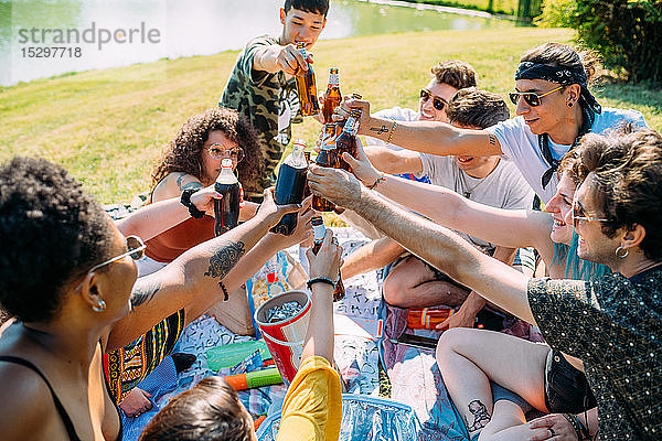 Eine Gruppe von Freunden entspannt sich und trinkt beim Picknick im Park auf Erfrischungsgetränke