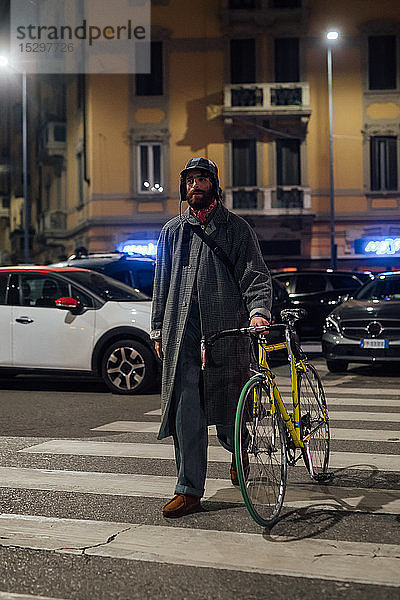 Bärtiger junger Mann  der mit dem Fahrrad auf einem Fußgängerüberweg geht